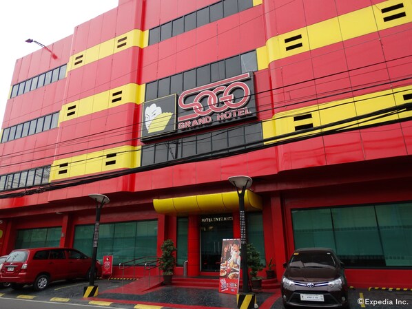 A hotel with a red and yellow facade, a prominent sign reading "GRAND HOTEL," and a visible entrance with a staircase. - Hotel Sogo EDSA Harrison (Pasay)