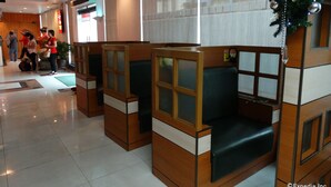 A hotel lobby with wooden seating areas, a reception desk, and a large window with a view of the building outside. - Hotel Sogo EDSA Harrison (Pasay)
