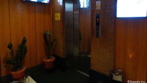An elevator interior with wooden walls, a potted plant, and a television mounted on the wall. - Hotel Sogo EDSA Harrison (Pasay)