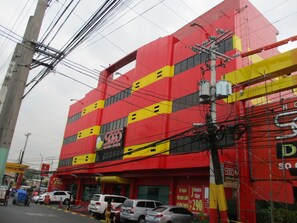 Un edificio rojo de varios pisos, con un cartel de hotel y varios coches aparcados.