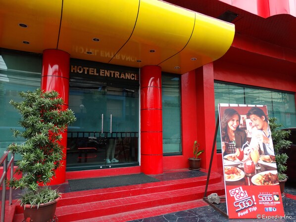 A hotel entrance with a red and yellow facade, a glass door, and steps leading up to the entrance. - Hotel Sogo EDSA Harrison (Pasay)