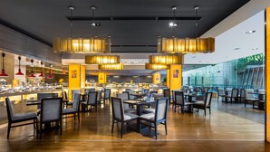 Un restaurant moderne doté de plusieurs espaces de restauration, d’un plancher en bois et d’un éclairage suspendu.