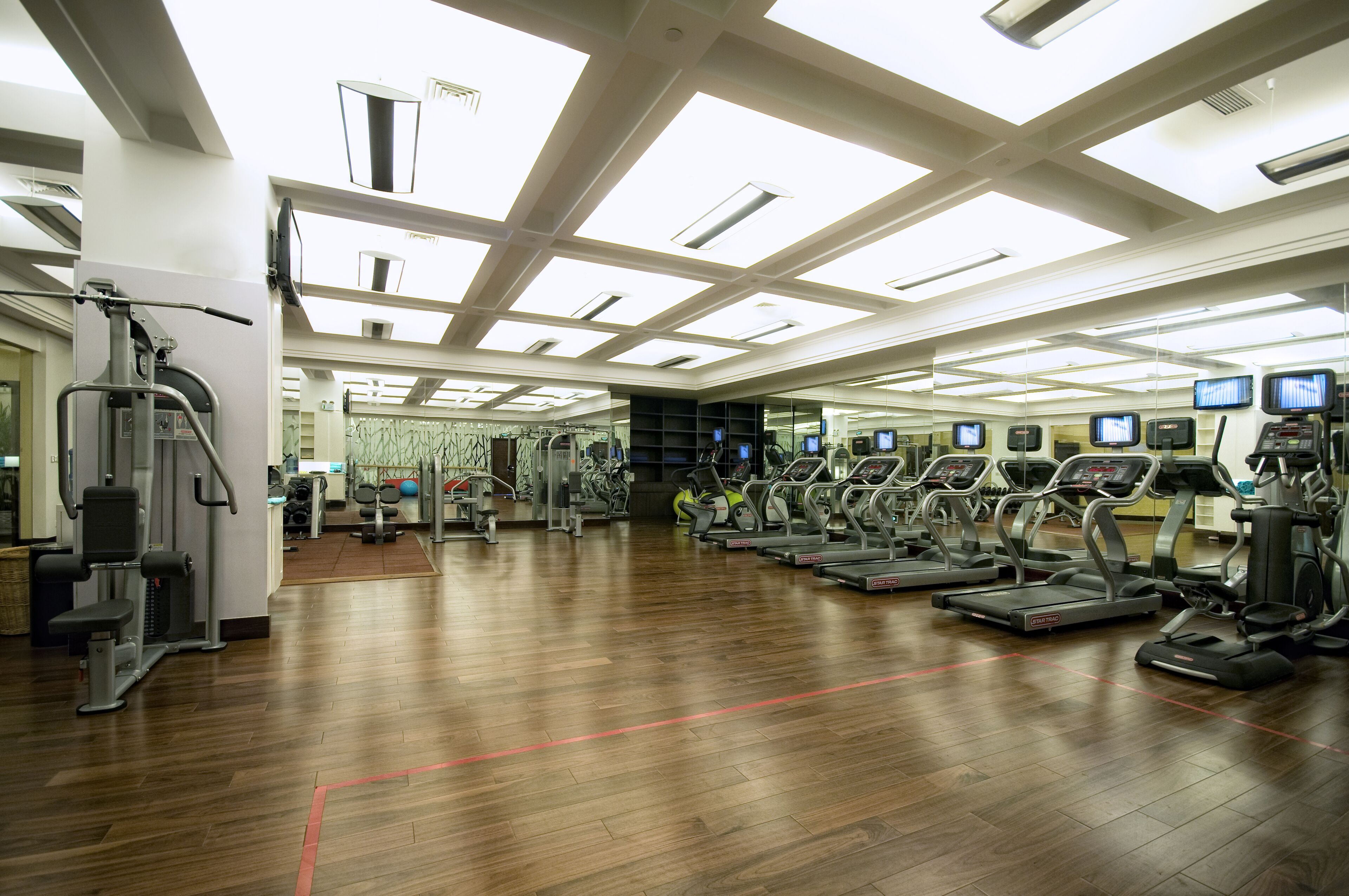A spacious gym with multiple treadmills, weight machines, and a mirrored wall.