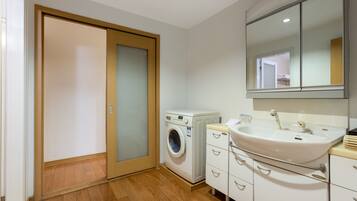 A modern bathroom with a washing machine, a sink, and a mirror.