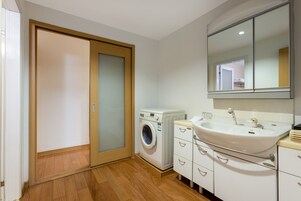 A modern bathroom with a washing machine, a sink, and a mirror.