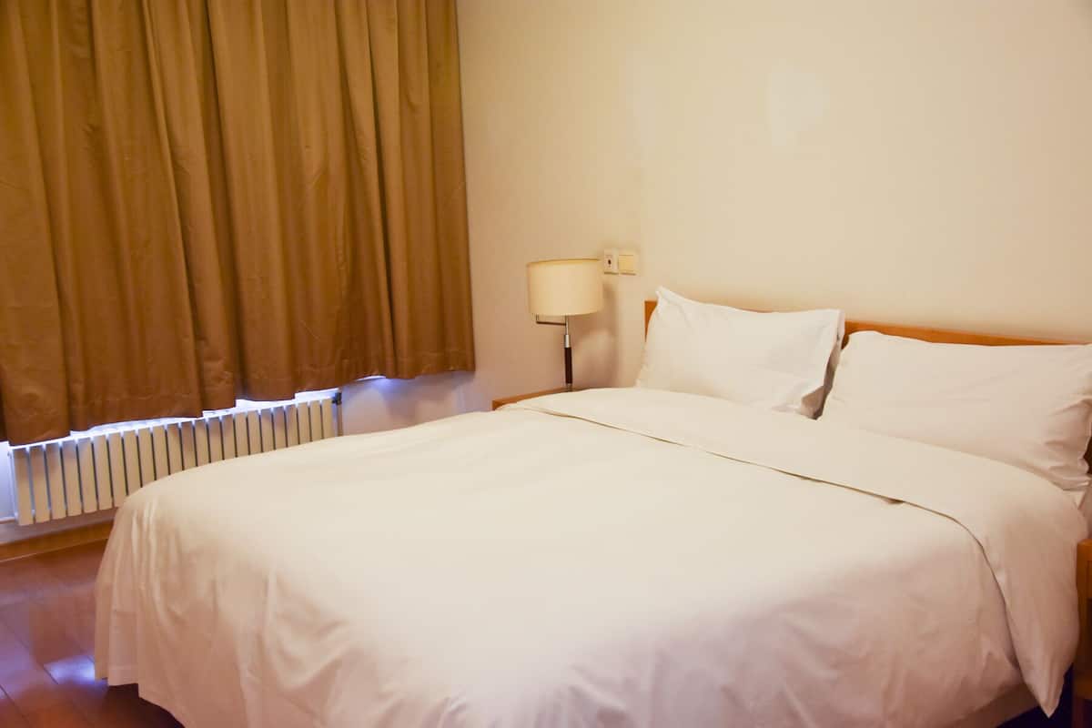 Een hotelkamer met een groot bed, een bedlampje en een raam met gordijnen.