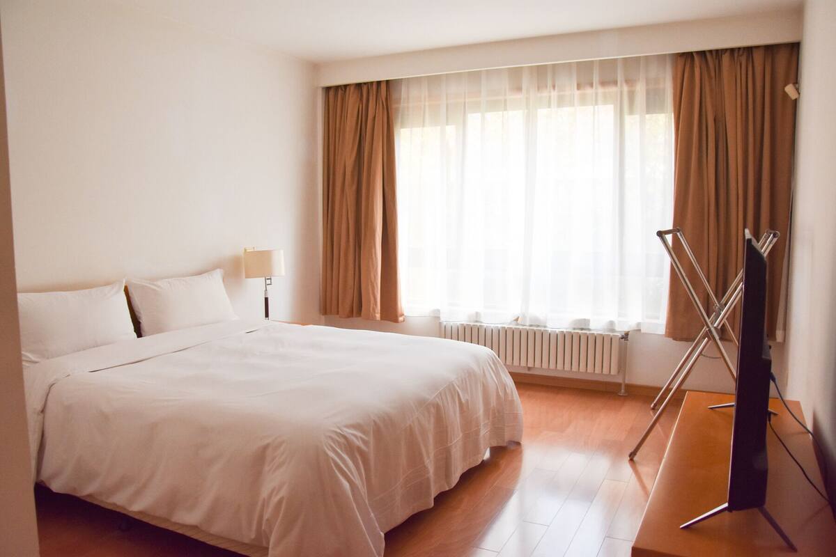 Een hotelkamer met een groot bed, een radiator, een lamp en een droogrek.
