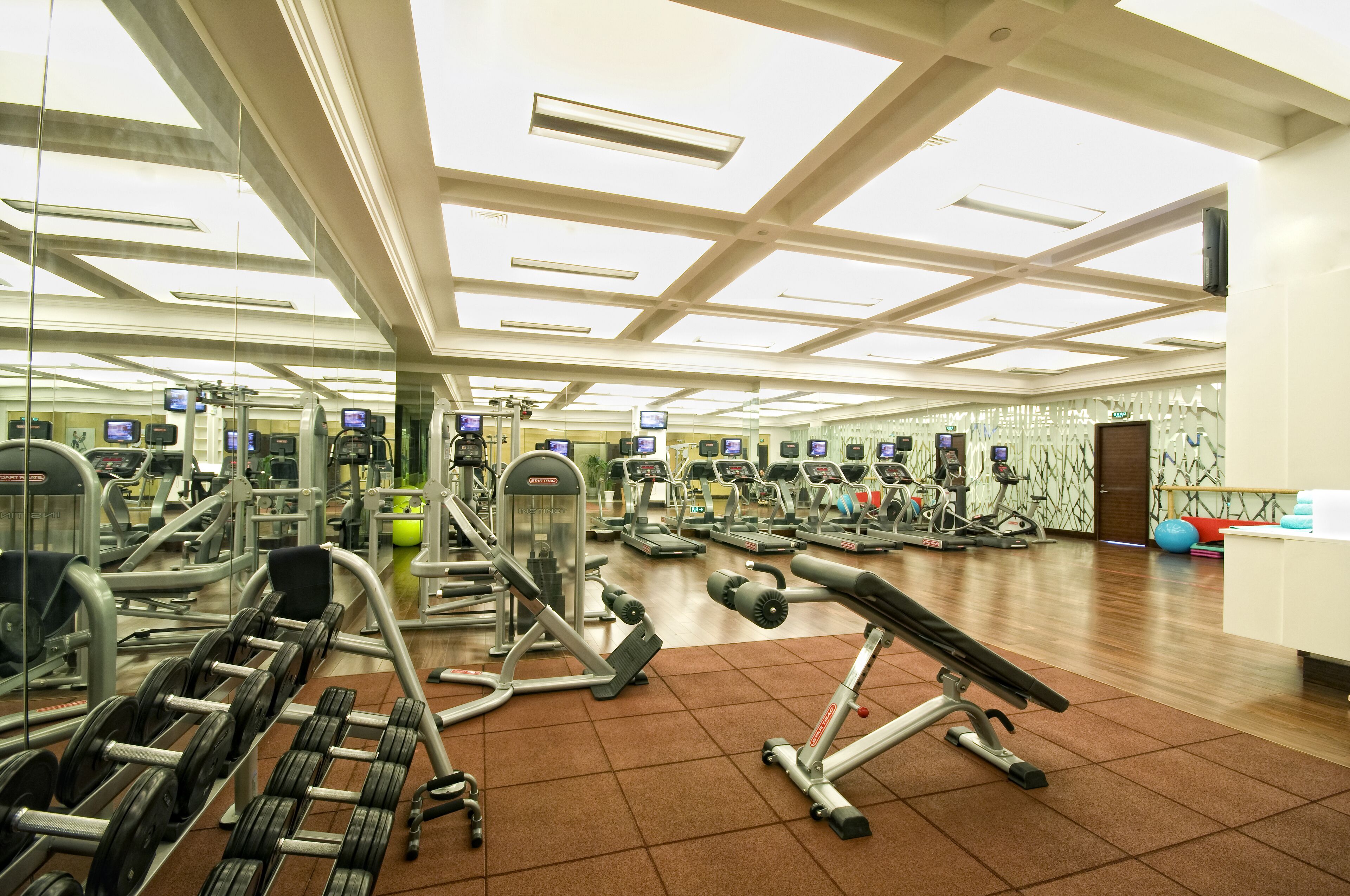 Une salle de sport équipée de divers appareils d’exercice, de miroirs et dotée d’un sol carrelé.