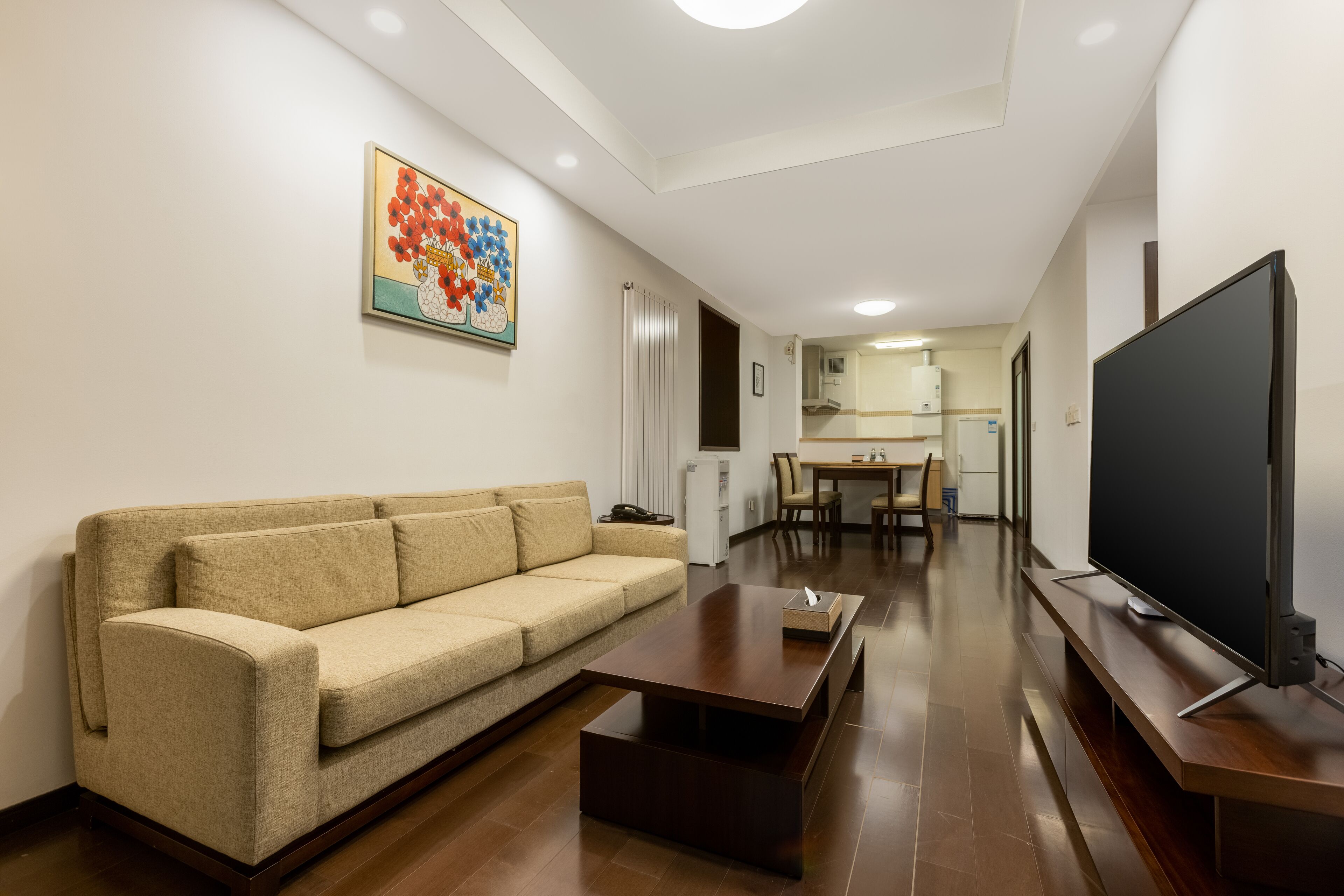 Una sala de estar con un sofá, una mesa de centro, un televisor y un comedor con sillas y una mesa.