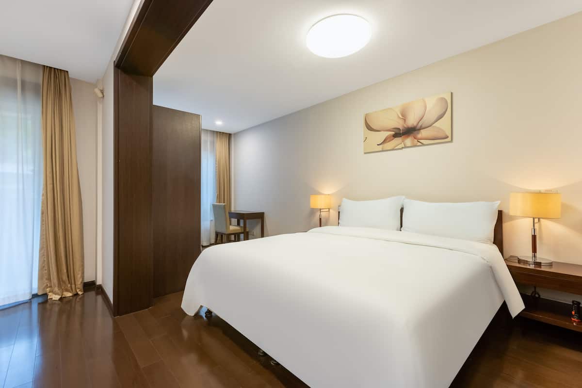 Een hotelkamer met een groot bed, twee bedlampen, een klein tafeltje en een stoel.
