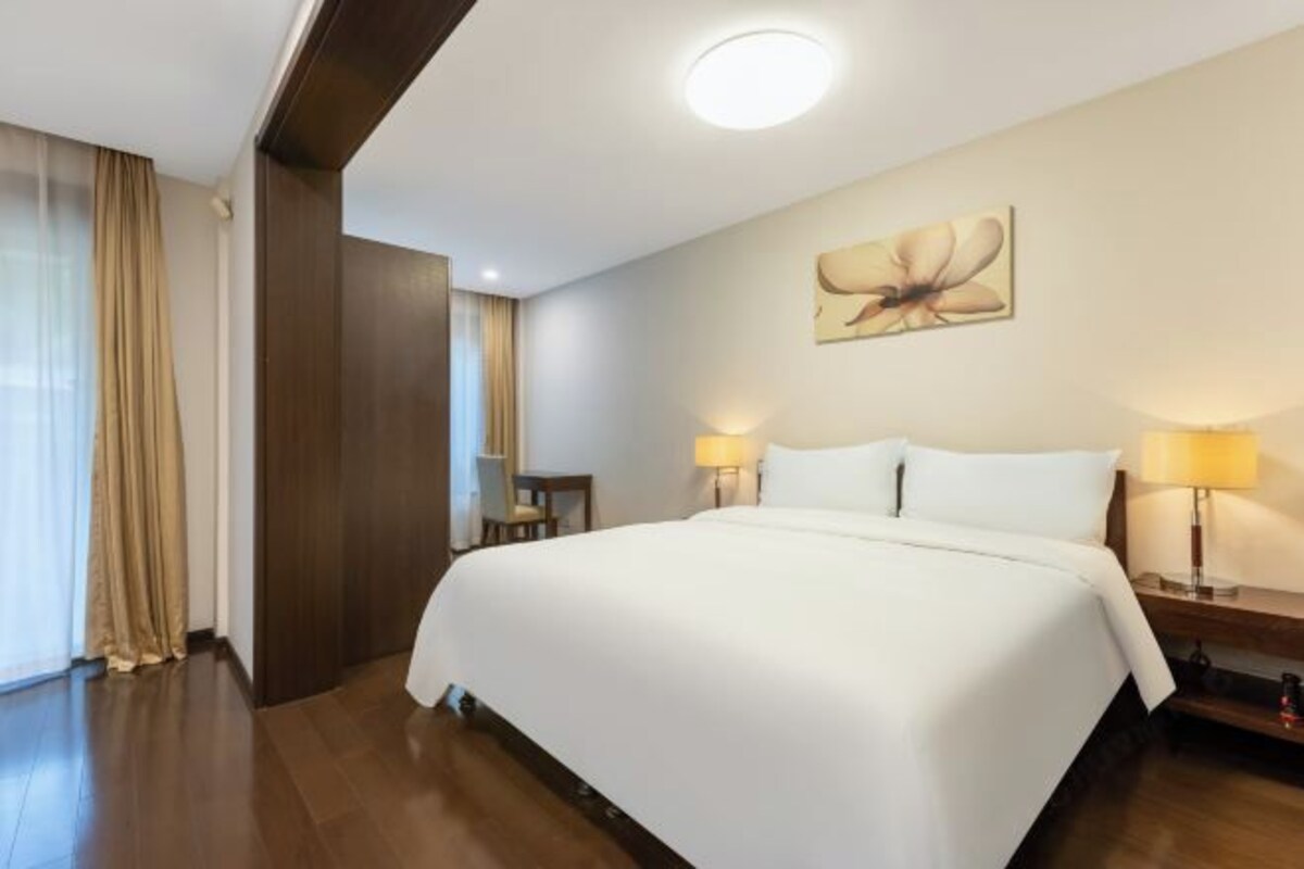 Une chambre d’hôtel avec un grand lit, deux lampes de chevet, un bureau et une chaise.