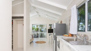 A modern kitchen with a marble countertop, a built-in oven, and a large window with a view of palm trees. - Muri Lagoon View Bungalows (Rarotonga)