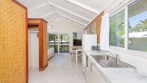 A modern kitchen with a large window, white cabinets, and a dining area with a table and chairs. - Muri Lagoon View Bungalows (Rarotonga)