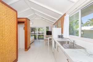 Una cocina moderna con un ventanal grande, armarios blancos y una zona de comedor con mesa y sillas.