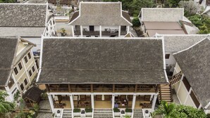 A traditional multi-story building with a tiled roof, a central courtyard, and surrounding greenery. - The View Pavilion (Luang Prabang)