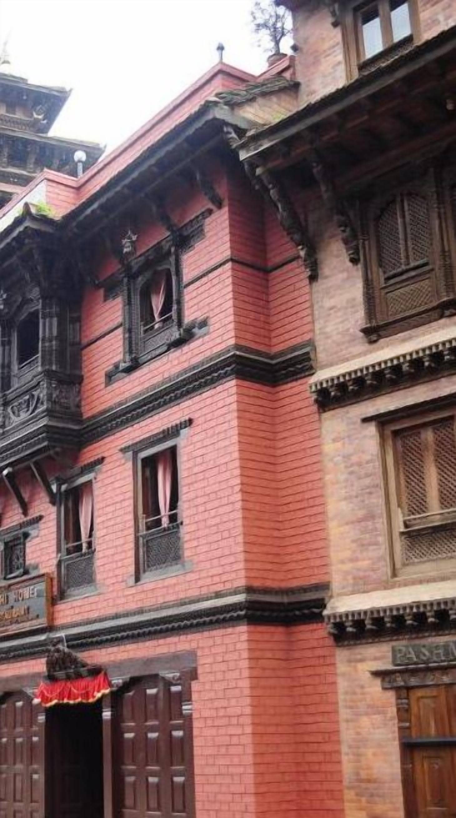 A building with a red brick facade, multiple windows with wooden frames, and traditional architectural details.