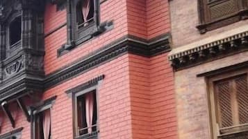 A building with a red brick facade, multiple windows with wooden frames, and traditional architectural details.
