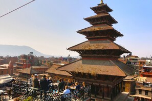 A traditional multi-tiered pagoda with a thatched roof, surrounded by a crowd of people. - Siddhi Home & Restaurant (Bhaktapur)