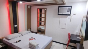 Een hotelkamer met een bed, een bureau, een stoel, een airconditioning en een televisie.
