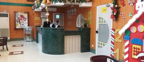 Un área de recepción con un mostrador curvo, una mesa de recepción y una puerta con la leyenda 'ENTRANCE'.