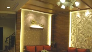Una sala de estar acogedora con sofá y sillones, una mesita de centro y una pared decorativa con estampado floral.