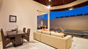 A modern interior with a dining area, a sofa, and a view of the outdoors. - Arsa Villa Bali (Seminyak)