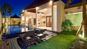 A modern house with a swimming pool, lounge chairs, and a well-maintained garden. - Arsa Villa Bali (Seminyak)