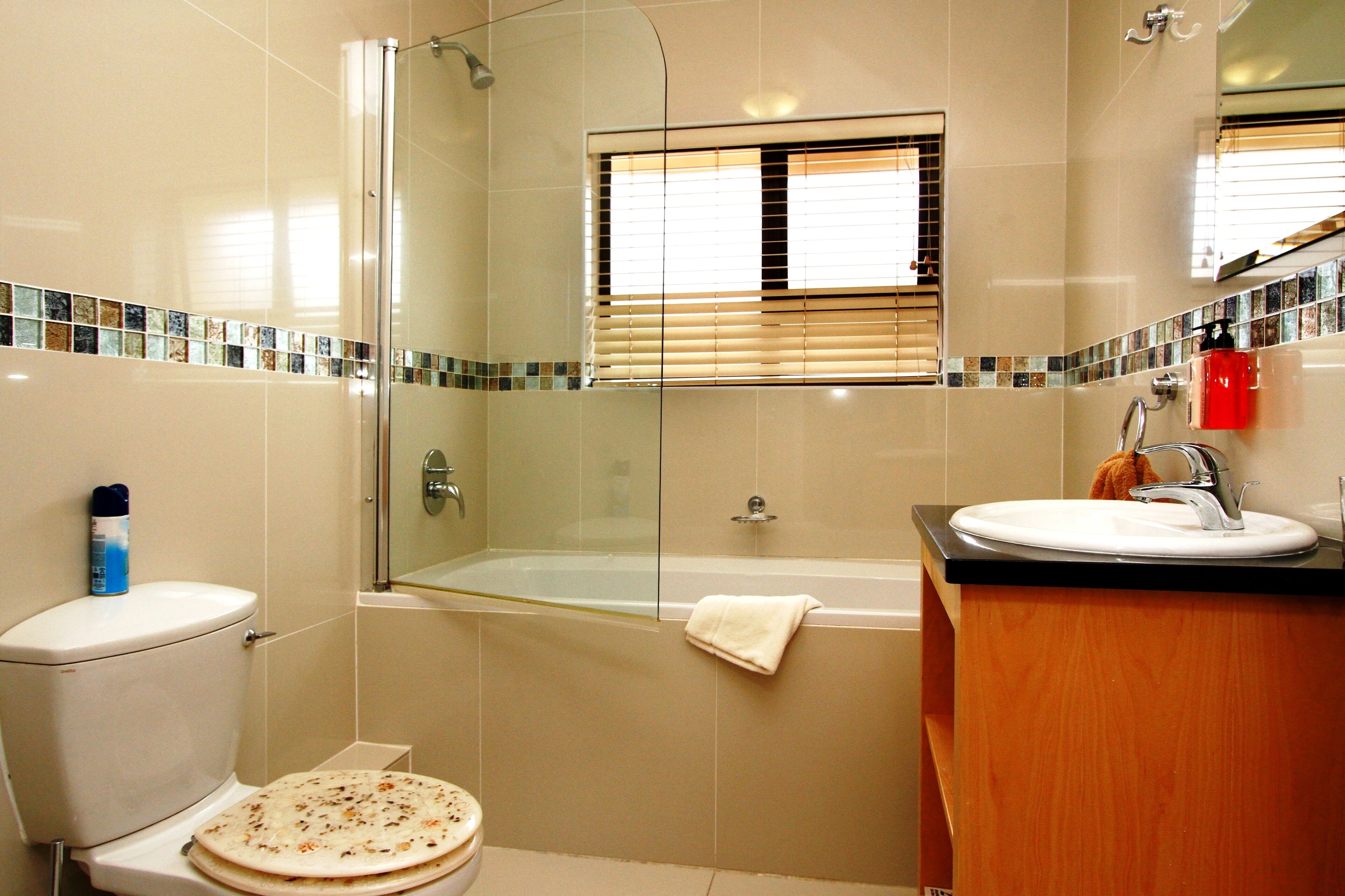 A bathroom with a glass-enclosed shower, a toilet, and a sink with a wooden vanity.