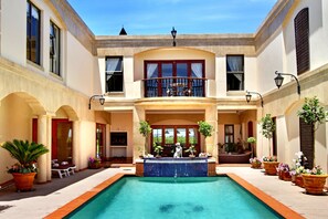 A pool with a tiled border, a balcony with a railing, and potted plants. - Casa Mia Guesthouse (Cape Town)