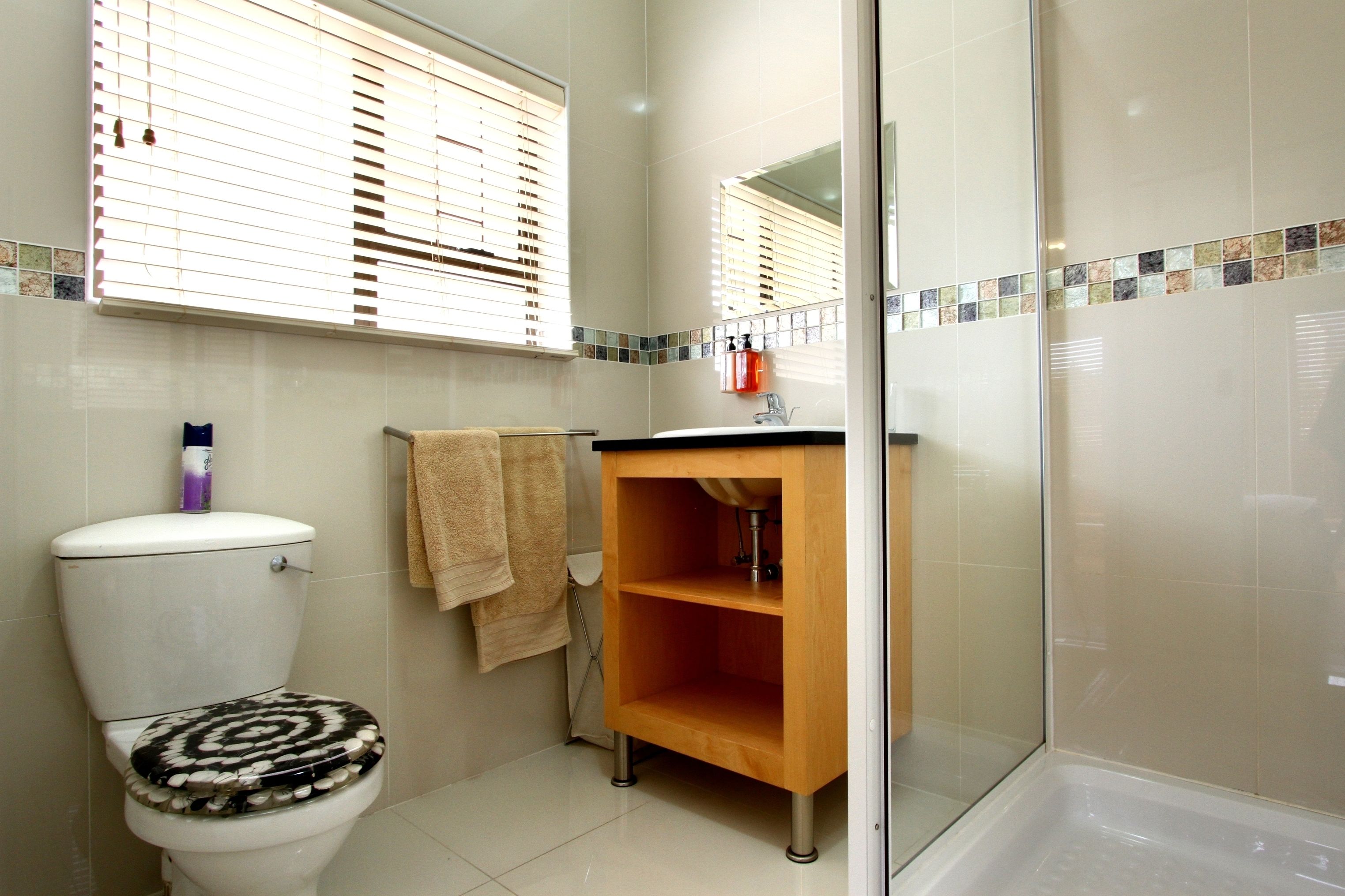 A bathroom with a toilet, a sink, a mirror, and a shower.