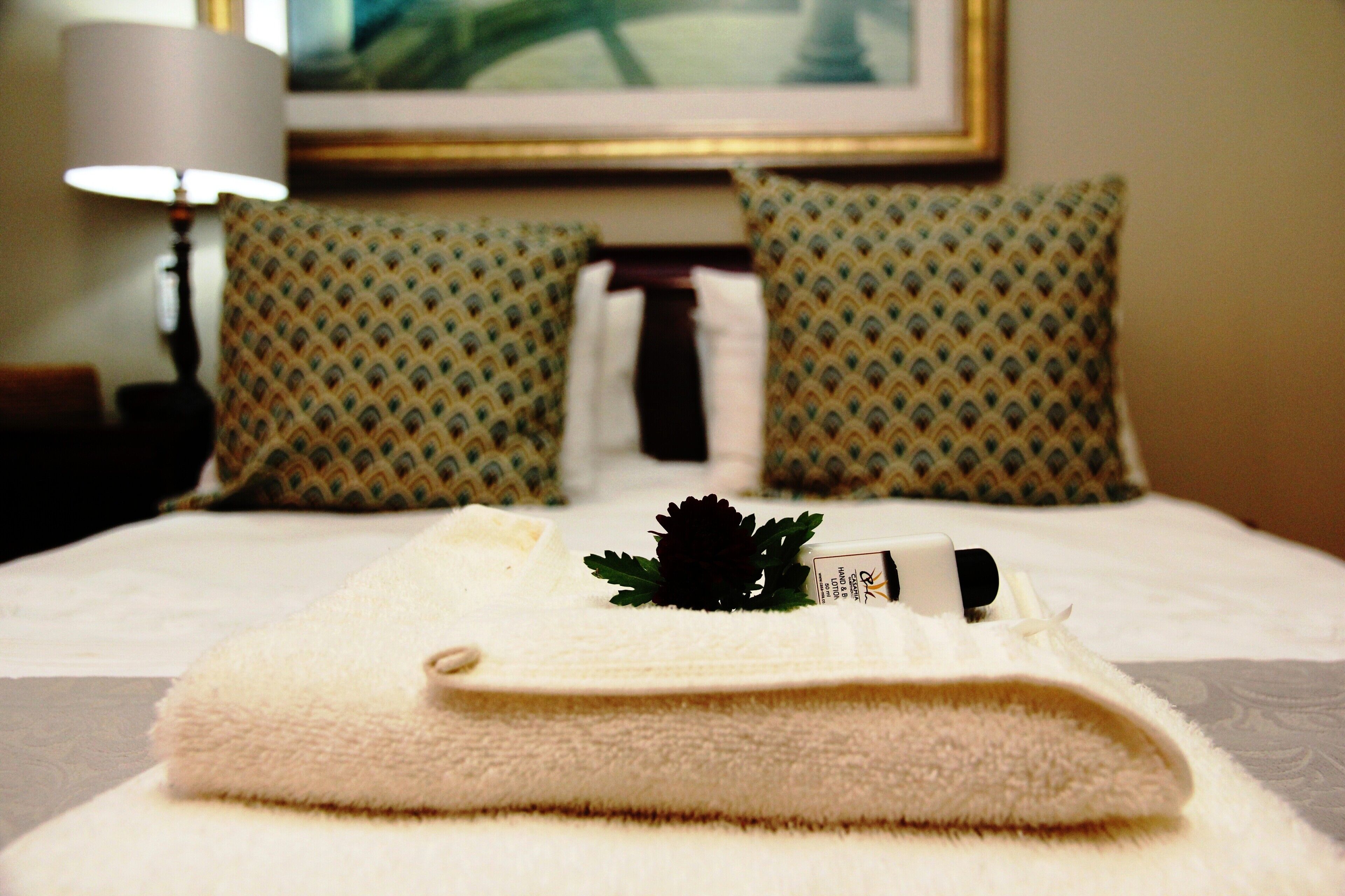 A neatly made bed with a folded towel and a small decorative item on top.