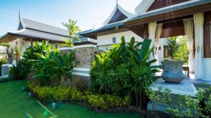 A modern house with a traditional roof, surrounded by lush greenery and a well-maintained lawn. - Pimann Buri Pool Villas Ao Nang Krabi - SHA Plus (Krabi)