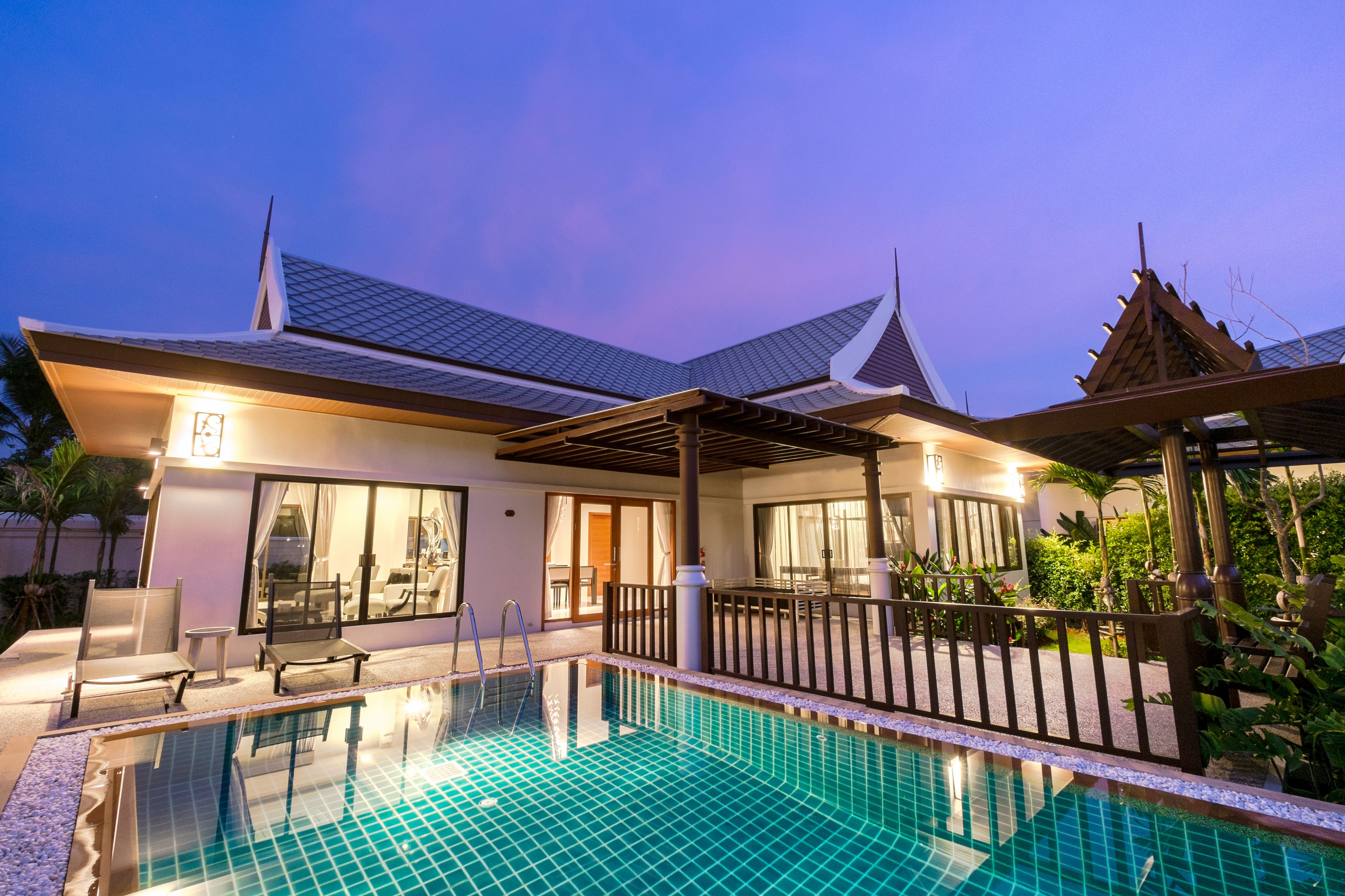 A modern hotel with a swimming pool, covered outdoor seating, and a traditional architectural style.
