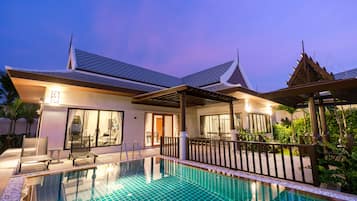 A modern hotel with a swimming pool, covered outdoor seating, and a traditional architectural style.