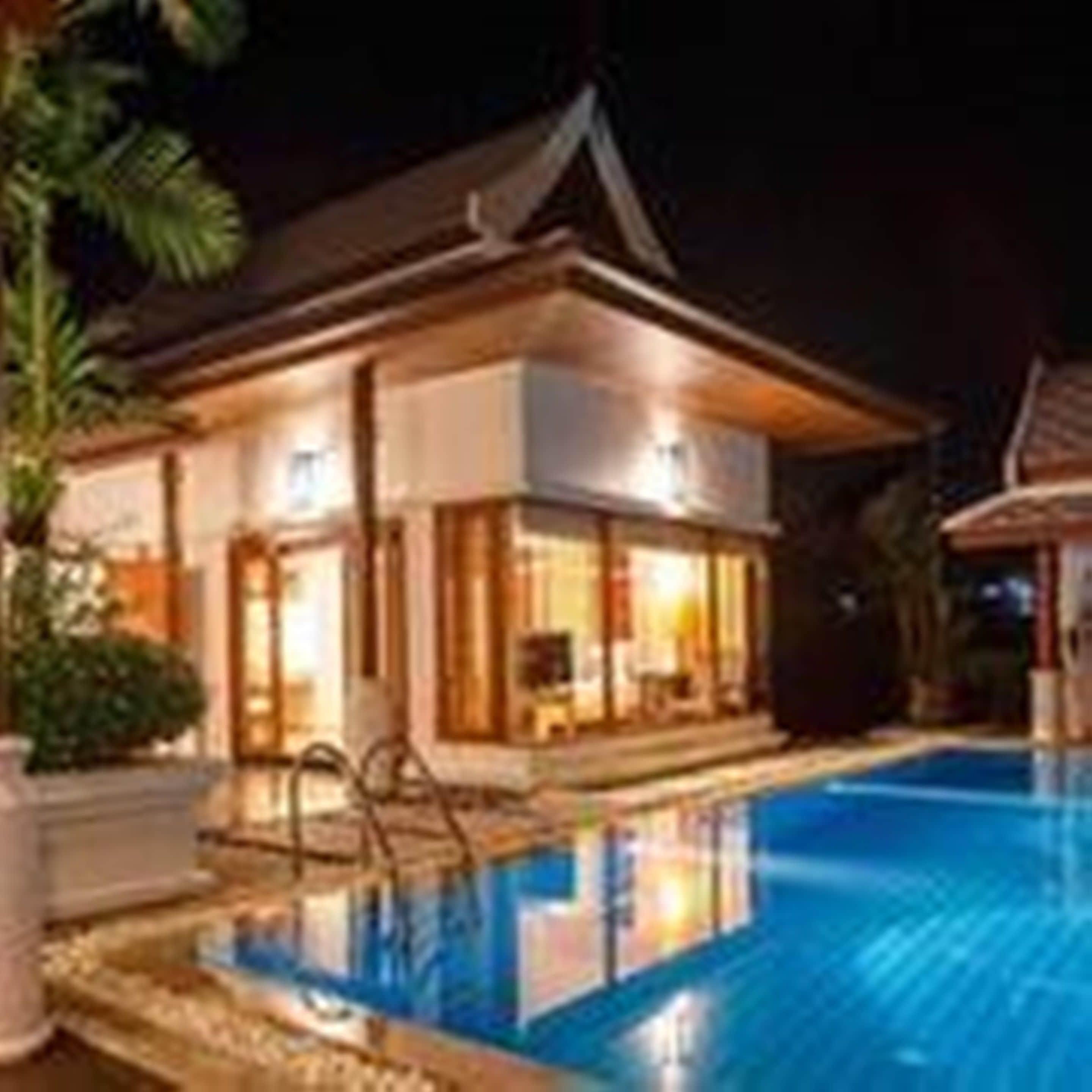 A modern hotel with a swimming pool, large windows, and a well-lit exterior.
