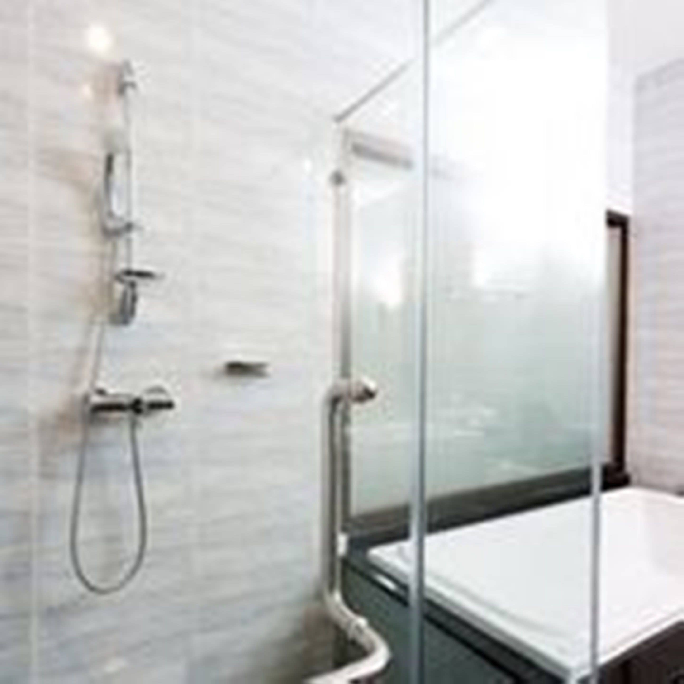 A modern bathroom with a glass-enclosed shower, a white bathtub, and a visible toilet.