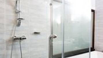 A modern bathroom with a glass-enclosed shower, a white bathtub, and a visible toilet.