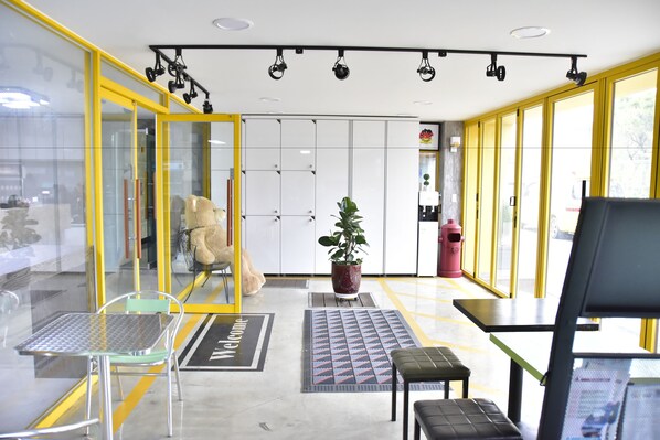 Un intérieur moderne avec des murs en verre, un paillasson, une plante en pot, un extincteur et un banc.