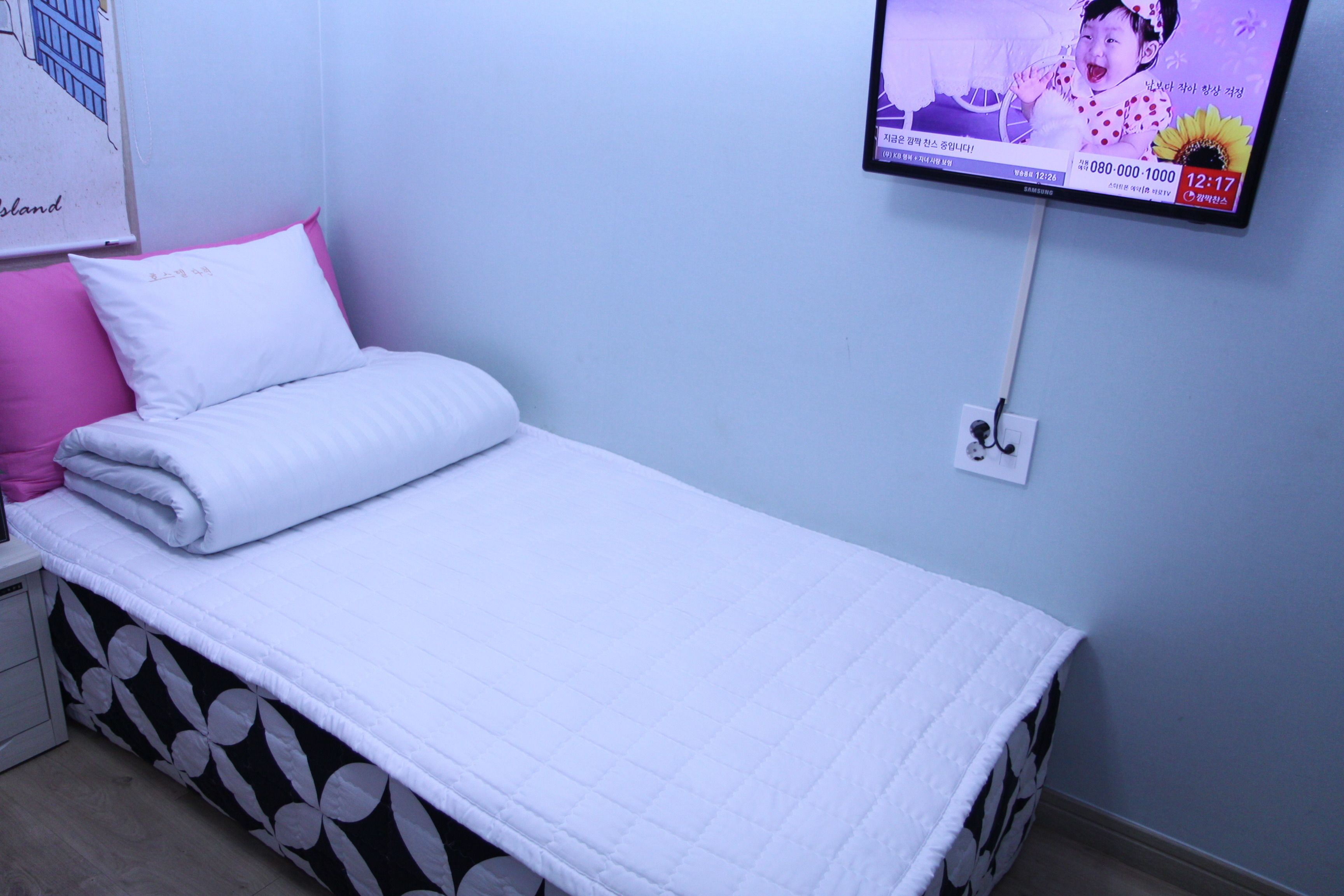 Uma cama de solteiro com roupa de cama branca e saia de cama preta e branca estampada.