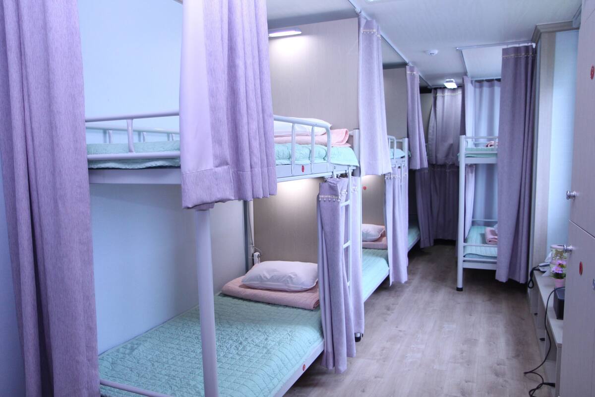 Ein Zimmer mit Etagenbetten, einem Schreibtisch und einem Kleiderschrank.