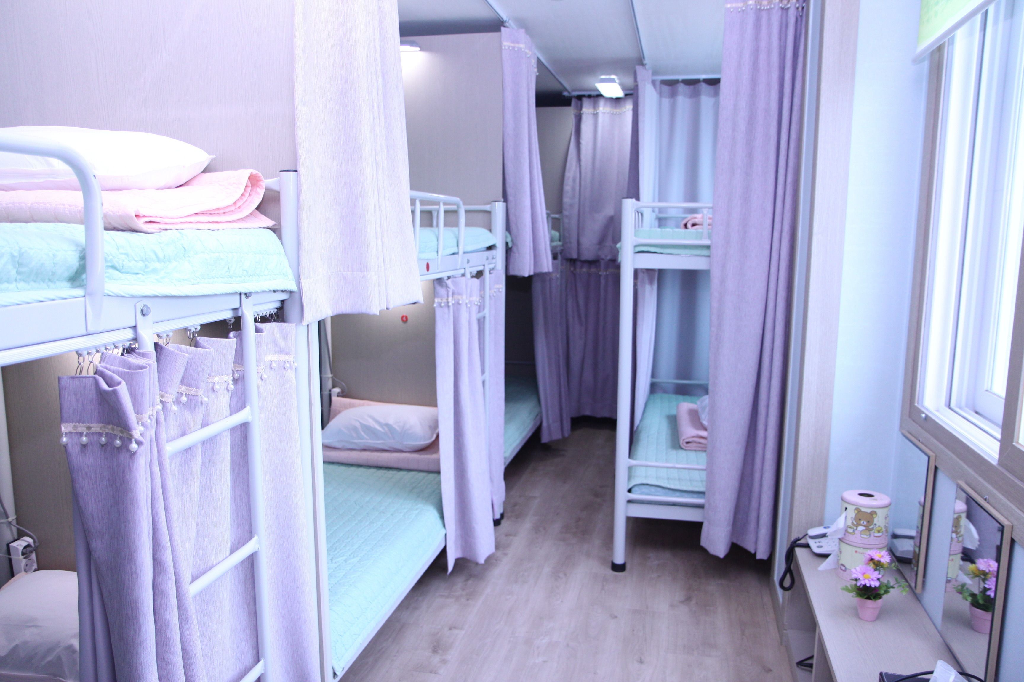 A room with bunk beds, a desk with a mirror, and a small window.