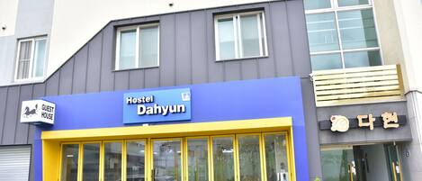 Un edificio con fachada azul y amarilla, un letrero que dice 'Hostel Dahyun' y un letrero de 'Guest House'.