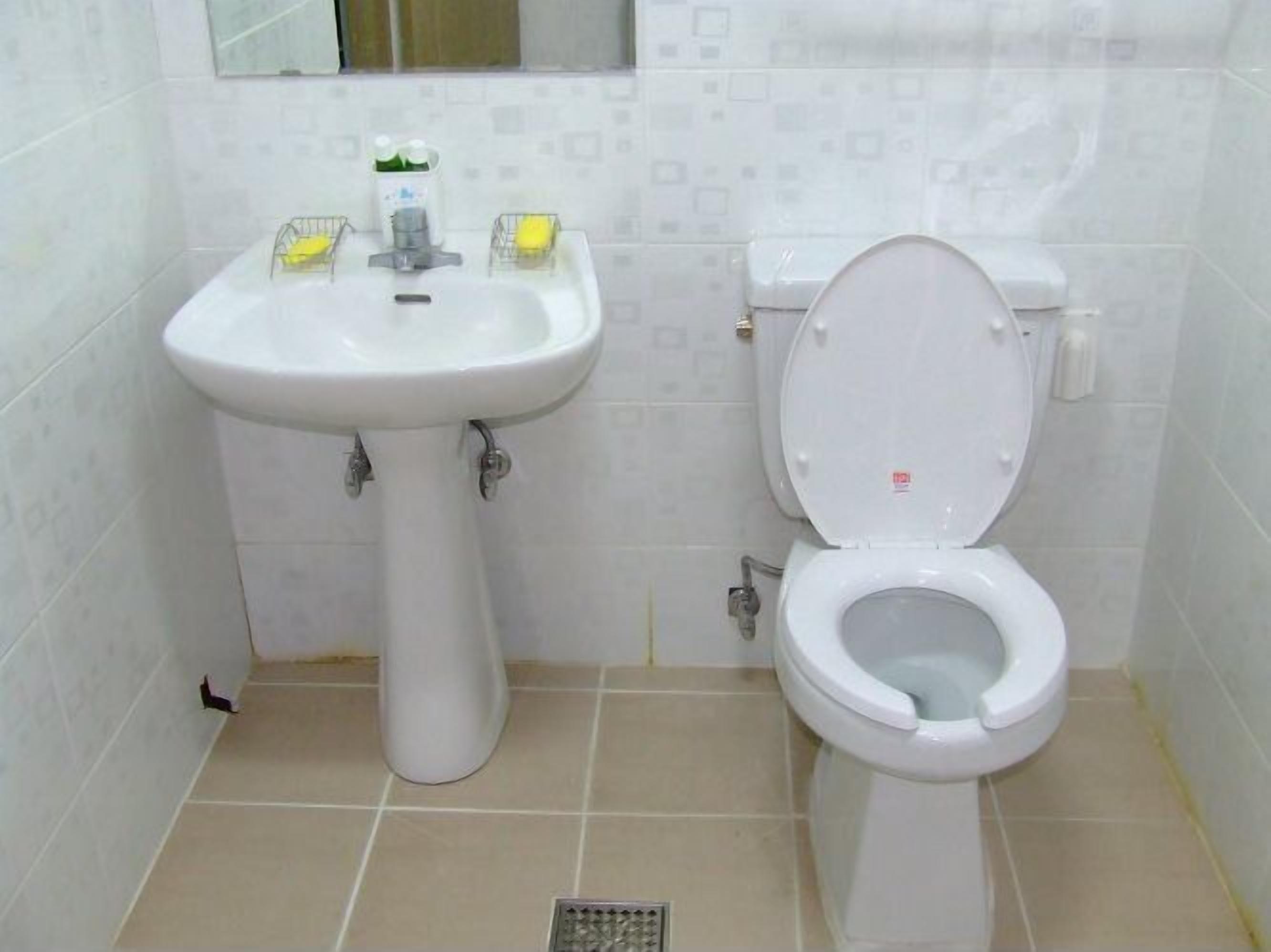 A bathroom with a white sink, toilet, and tiled walls.