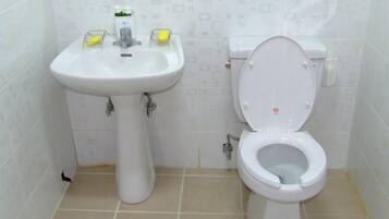 A bathroom with a white sink, toilet, and tiled walls.