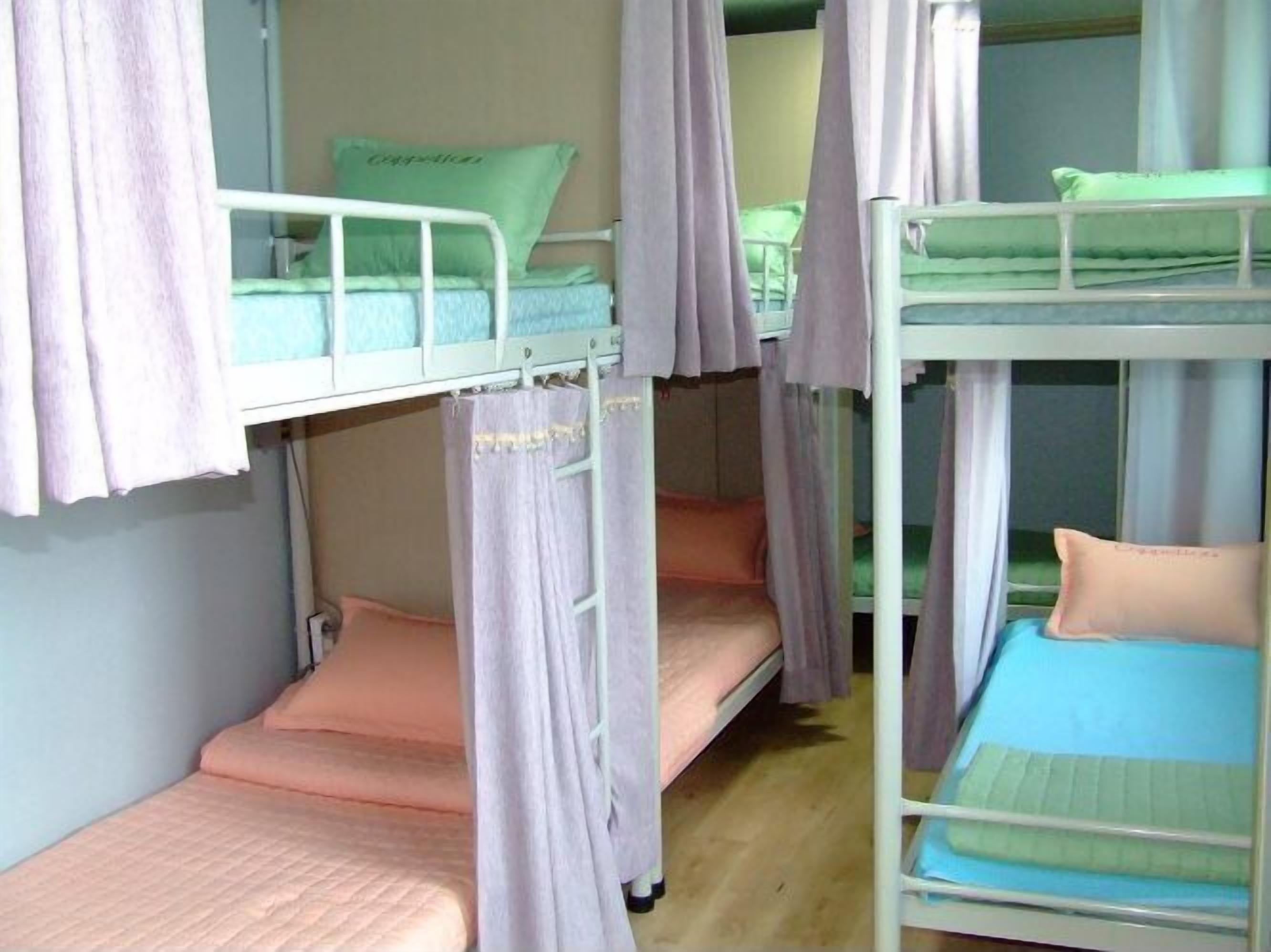 Une chambre de dortoir avec des lits superposés, chacun étant équipé d’un oreiller et d’une couverture.