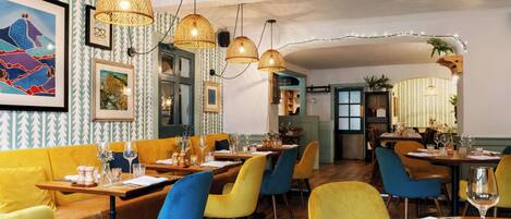 A restaurant with wooden tables, colorful chairs, and hanging lamps.
