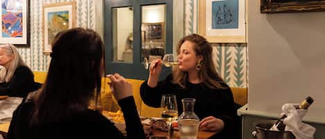 Un comedor con una mesa, sillas, una botella de champán y un cuadro en la pared.