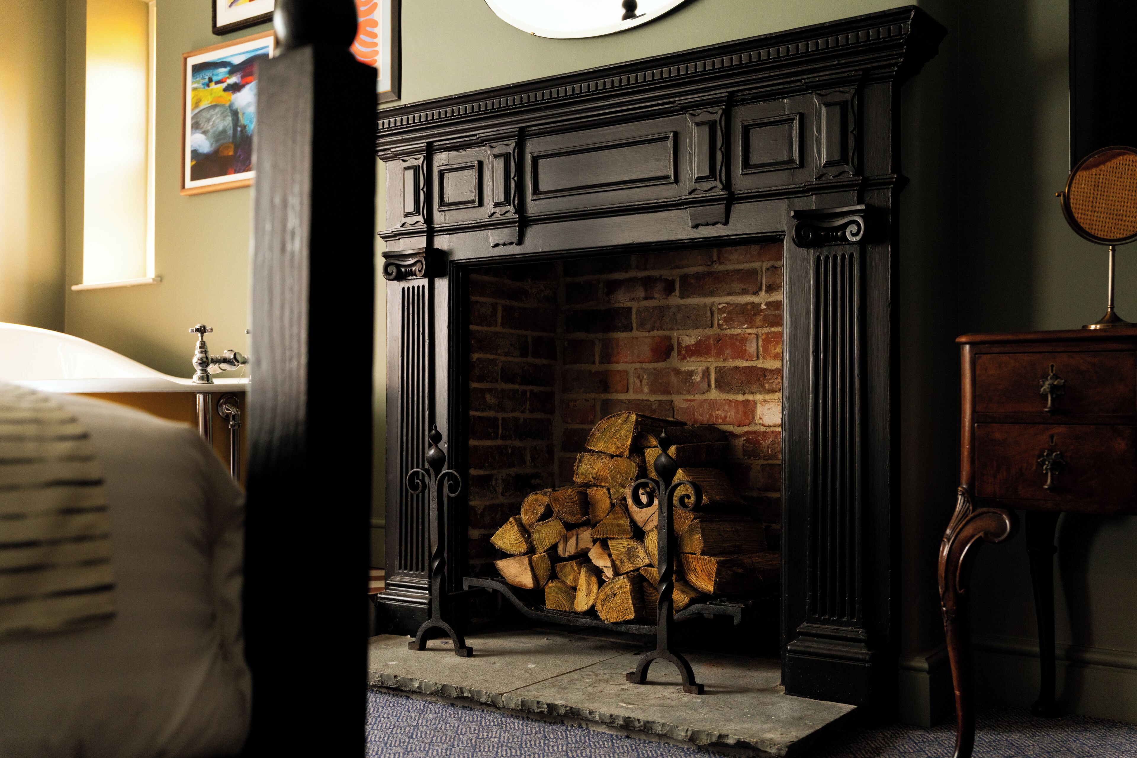 Una habitación con chimenea, una cama, un aparador y un reloj en la pared.