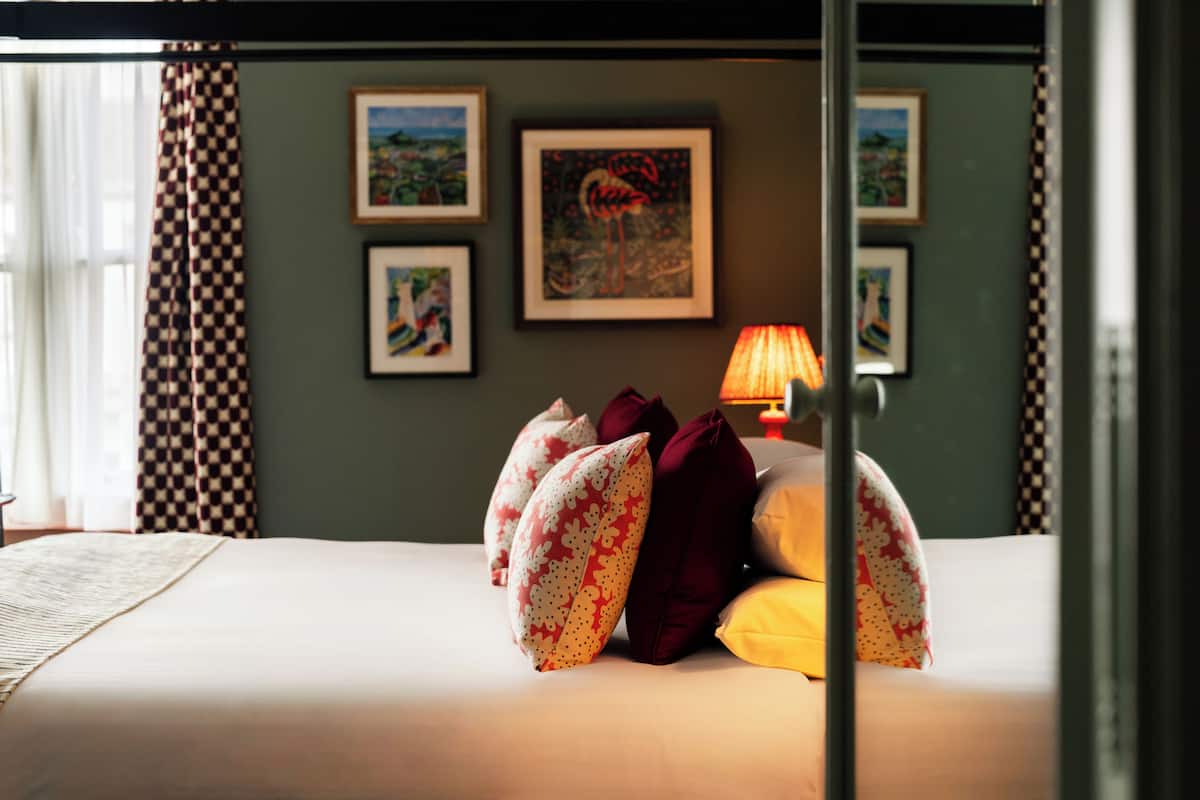 A neatly made bed with patterned pillows, a bedside lamp, and framed artwork on the wall.
