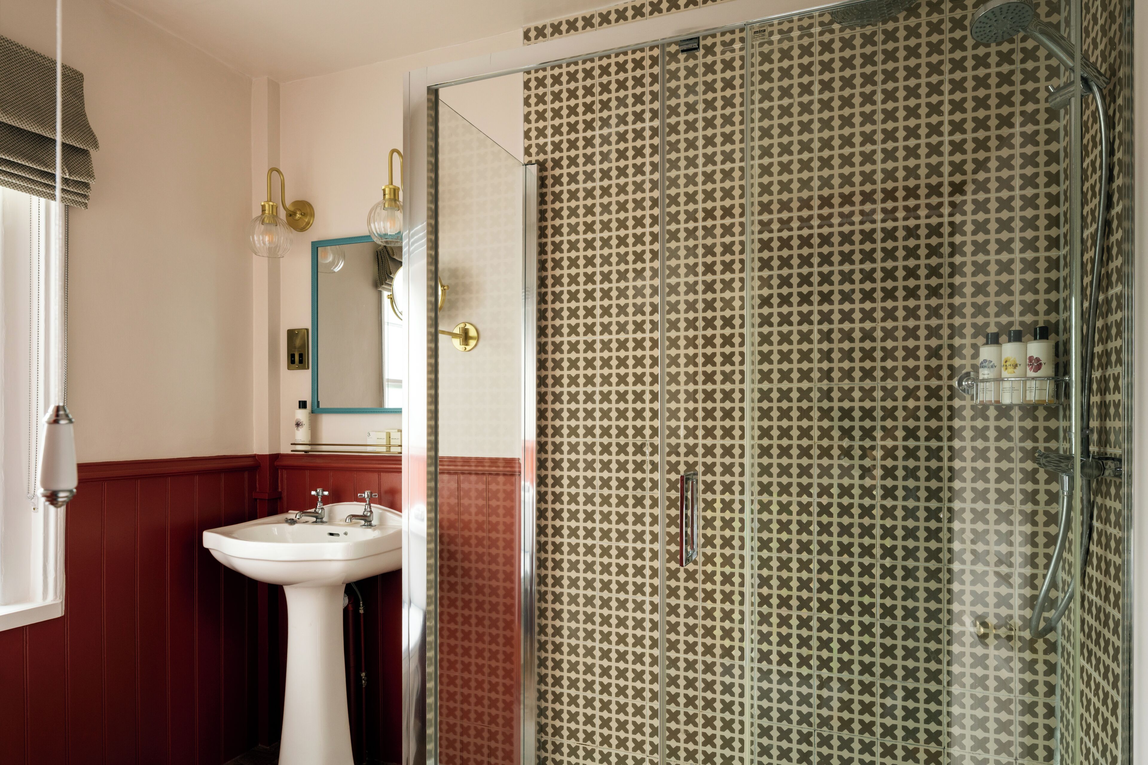 A bathroom with a glass shower enclosure, a white sink, and a mirror.